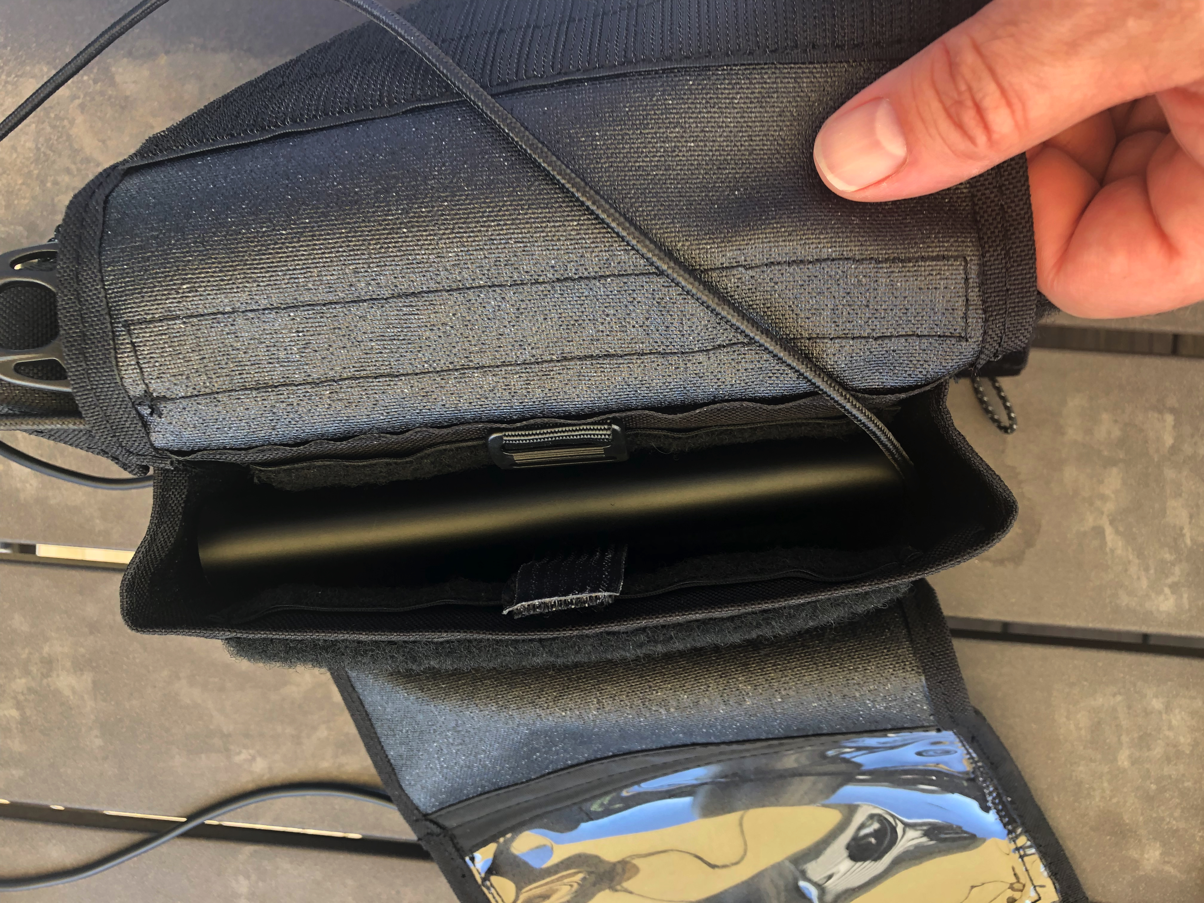 The front pocket holds the same battery with room to spare, making it a much better choice. There’s a small (i.e. 15x40mm) pass through opening to the main compartment